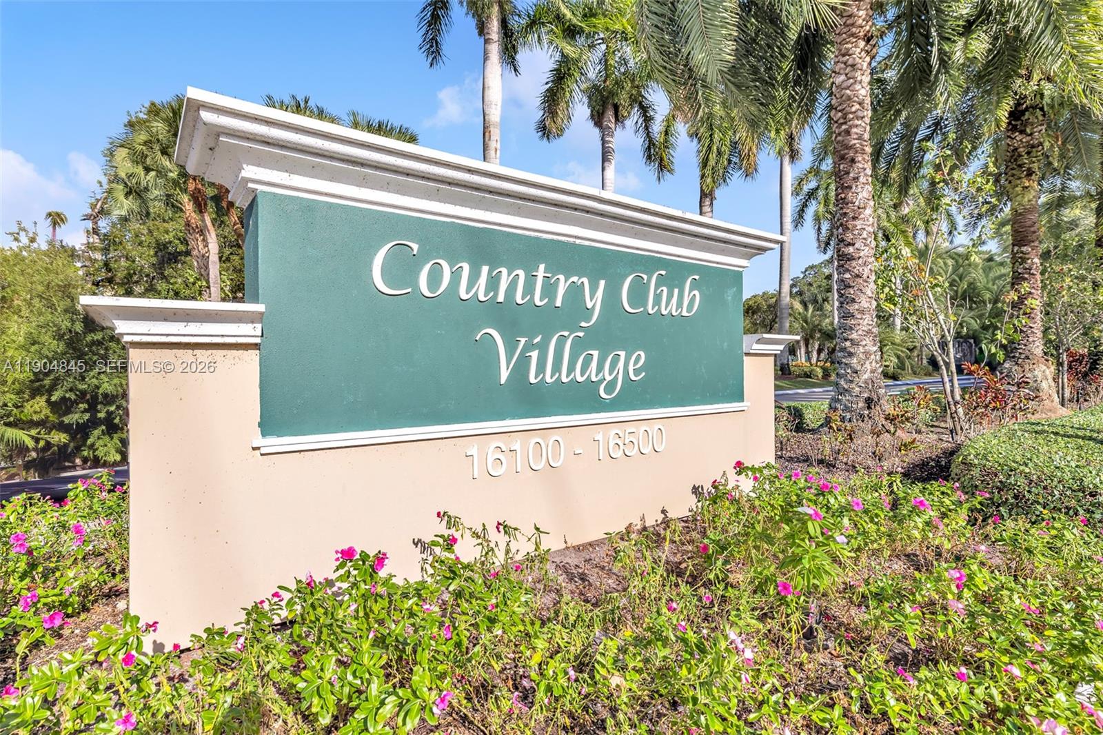 A green and beige monument sign displays the name Country Club Village with palm trees — 16300 Golf Club Rd # 408, Weston FL 33326, WESTON, FL