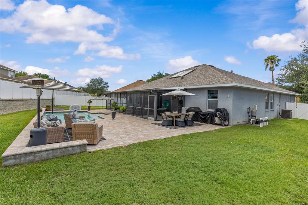 A rectangular swimming pool with a sun shelf and water feature sits on a paved patio — 14158 LEYBOURNE WAY, SPRING HILL, FL