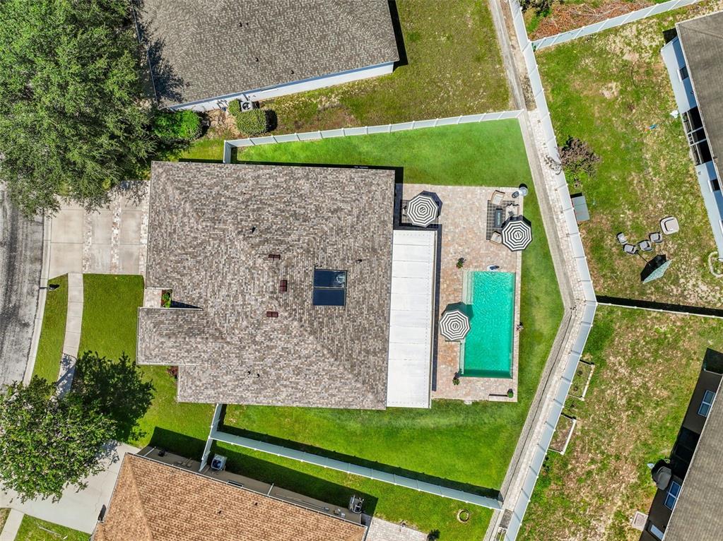 An aerial view of a house with a shingled roof, swimming pool, and fenced yard — 14158 LEYBOURNE WAY, SPRING HILL, FL