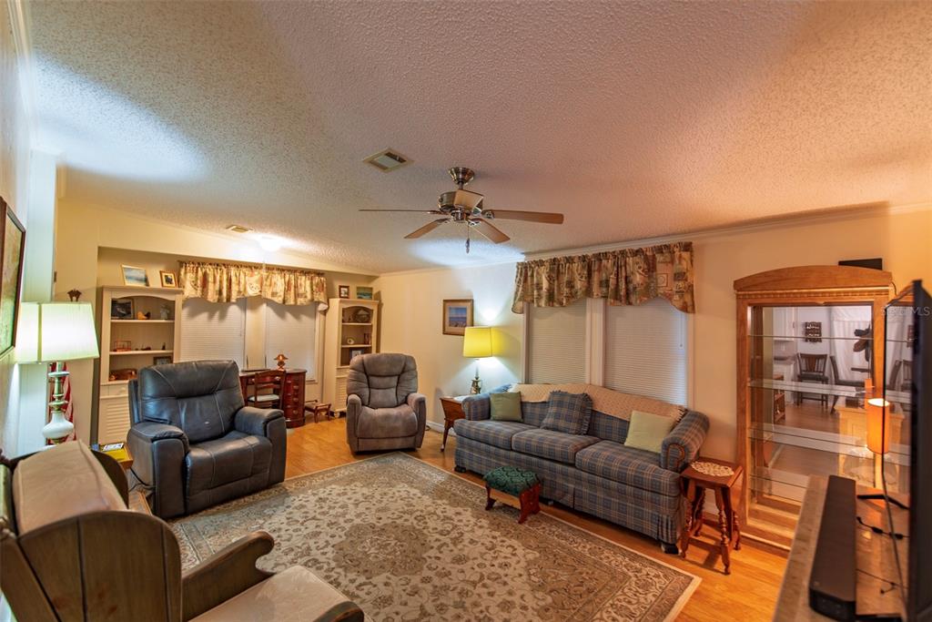 A living room features a plaid sofa, two recliners, a patterned rug, and a ceiling fan — 3 ROTTERDAM DRIVE, PUNTA GORDA, FL