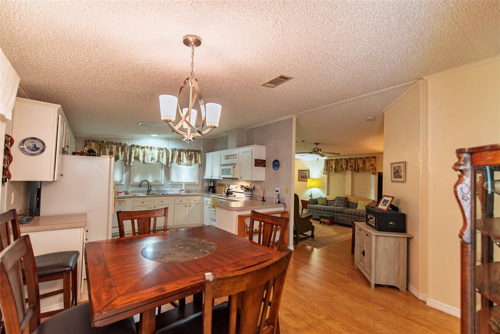 A dining area with a wooden table and chairs opens into a kitchen and living room — 3 ROTTERDAM DRIVE, PUNTA GORDA, FL