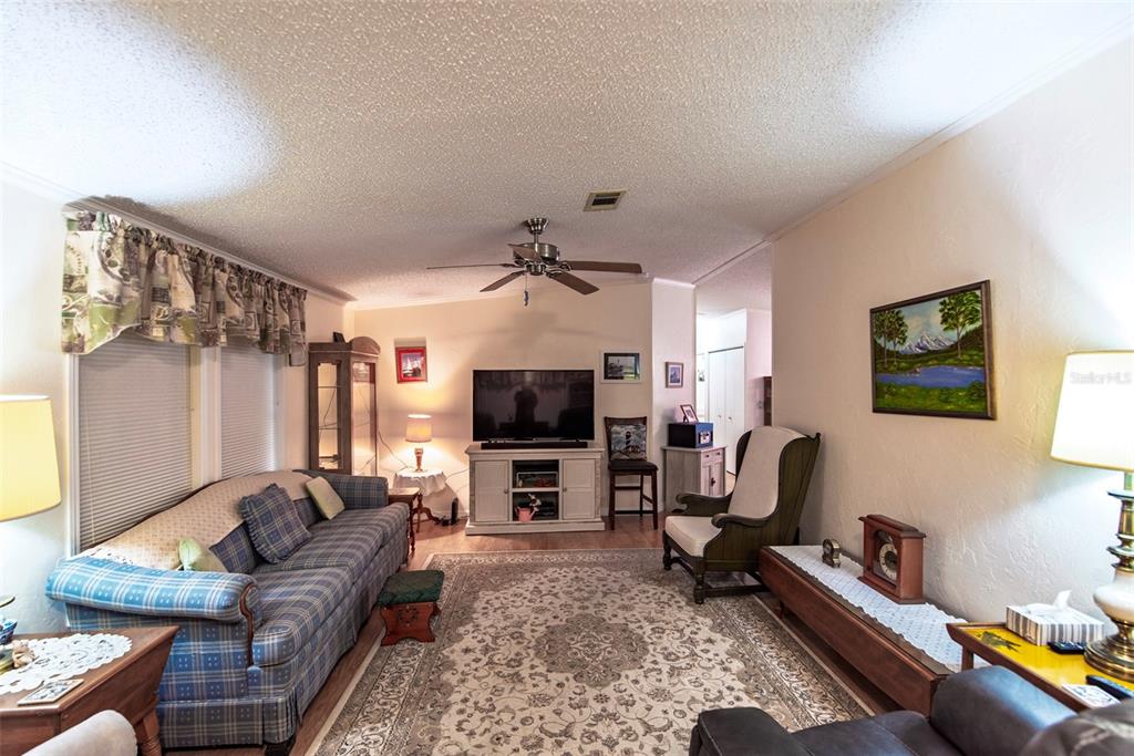 A living room features a plaid sofa, a patterned area rug, and a television console — 3 ROTTERDAM DRIVE, PUNTA GORDA, FL
