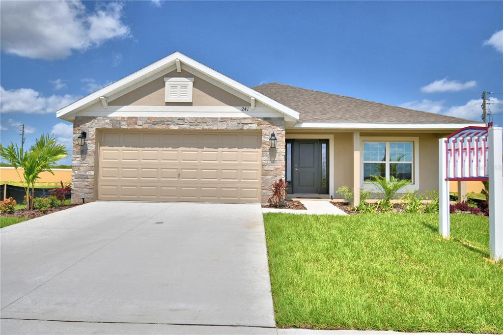 A single-story suburban house with a stone-accented garage, beige siding, and a concrete driveway — 241 PIAVE STREET, HAINES CITY, FL