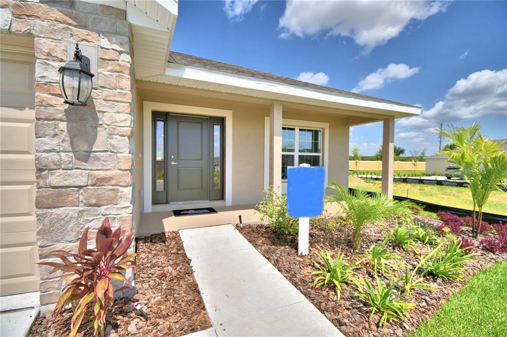 A front entrance with a stone facade, a dark door, and a concrete walkway — 241 PIAVE STREET, HAINES CITY, FL