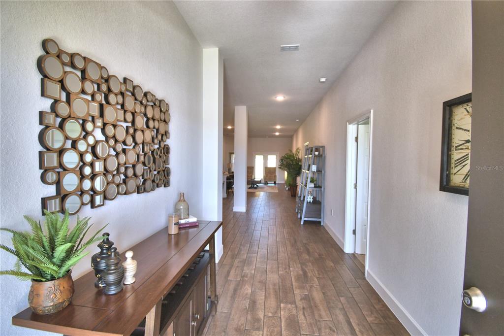 A long entryway features wood-look tile flooring, a console table, and a large mirror display — 241 PIAVE STREET, HAINES CITY, FL