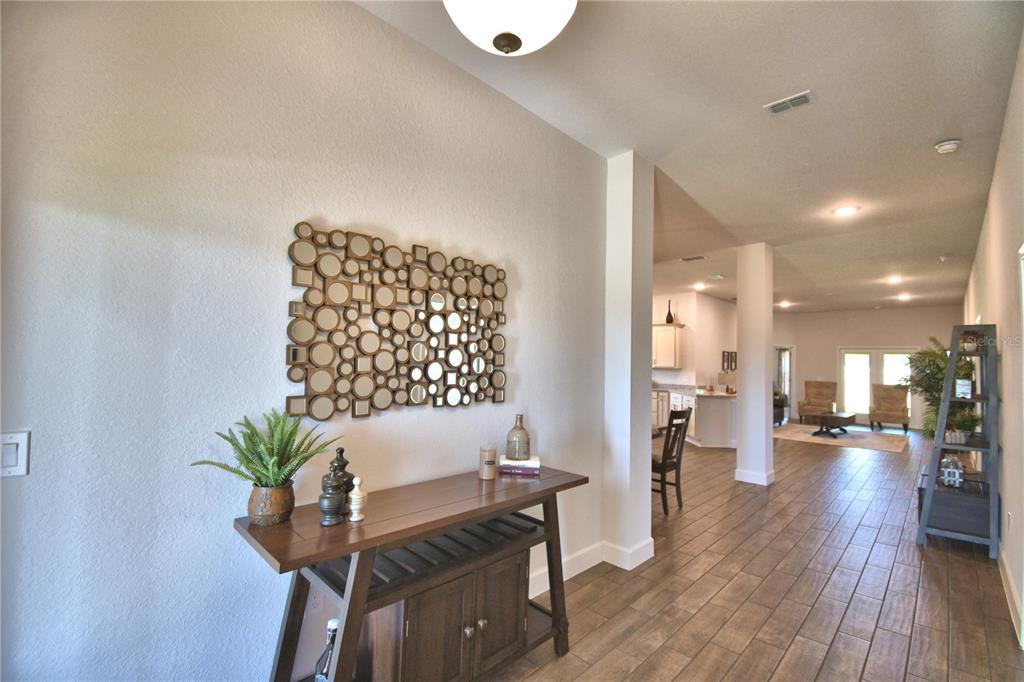 A wooden console table with decor sits in a foyer with tile flooring and mirrors — 241 PIAVE STREET, HAINES CITY, FL