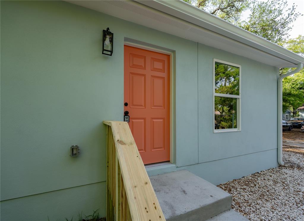A light green exterior wall features an orange front door, a window, and wooden stairs — 767 1/2 19TH AVENUE S, ST PETERSBURG, FL