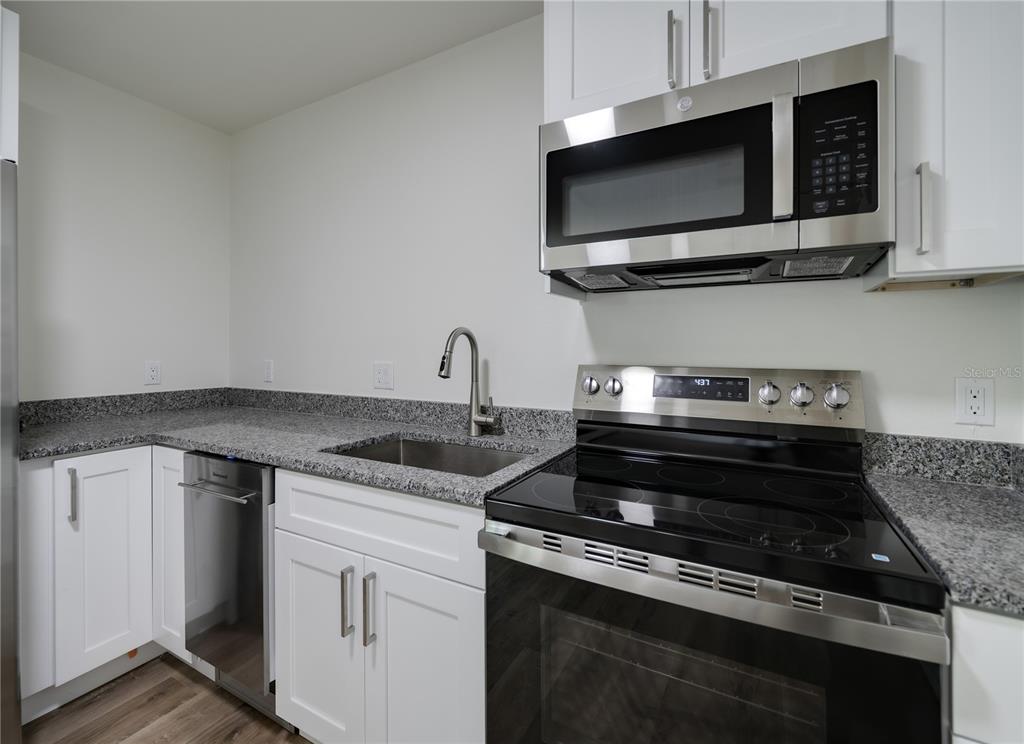 A kitchen features white cabinets, granite countertops, and stainless steel appliances — 767 1/2 19TH AVENUE S, ST PETERSBURG, FL