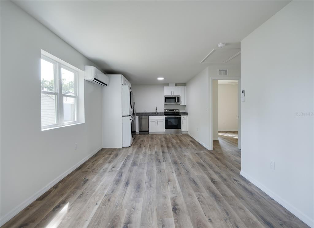 A kitchen with stainless steel appliances, white cabinets, and wood-look flooring in an open room — 767 1/2 19TH AVENUE S, ST PETERSBURG, FL