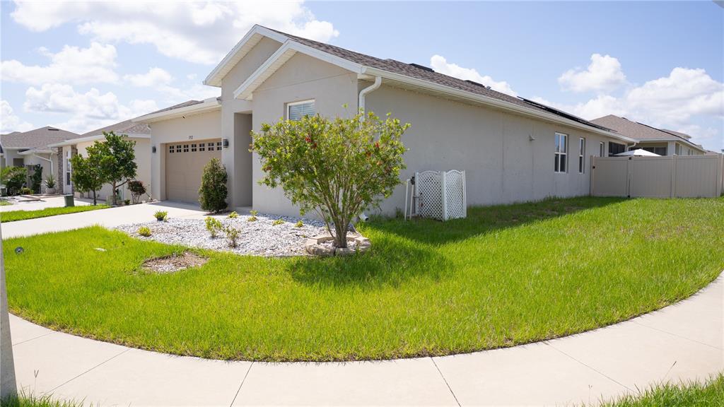 A beige single-story house with a garage, a landscaped front yard, and a white fence — 1932 CHICKASAW BOULEVARD, DAVENPORT, FL