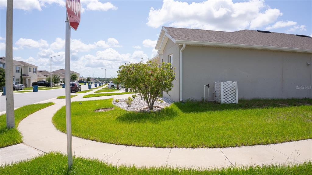 A view of a suburban street corner with a sidewalk, a stop sign, and a house — 1932 CHICKASAW BOULEVARD, DAVENPORT, FL