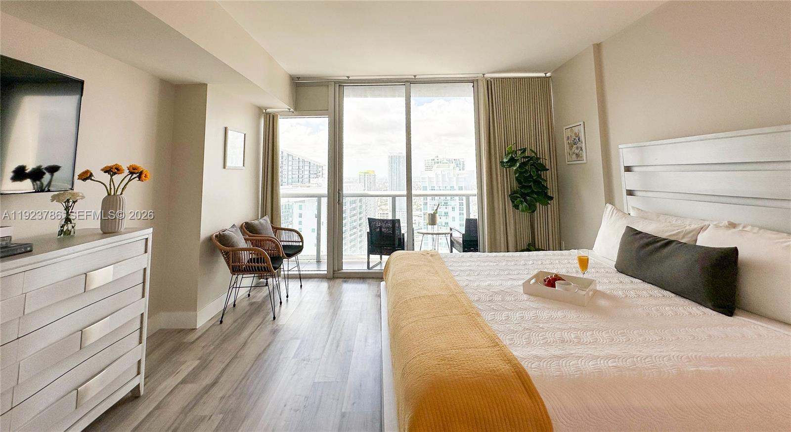 A bedroom features a bed with yellow bedding, a white dresser, and a balcony view — 485 Brickell Ave # 4405, Miami FL 33131, MIAMI, FL
