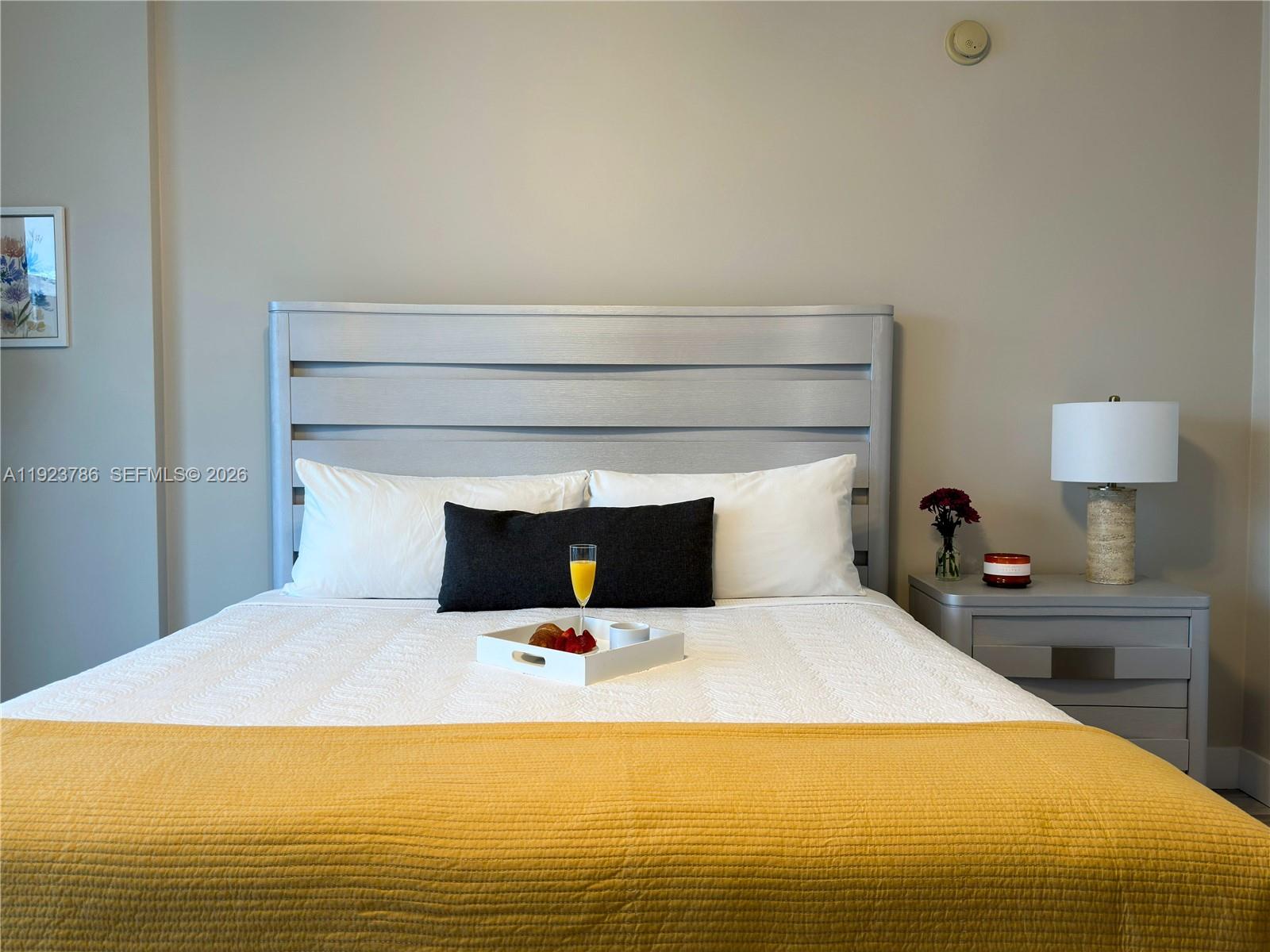 A bedroom features a bed with a gray headboard, white bedding, and a yellow throw — 485 Brickell Ave # 4405, Miami FL 33131, MIAMI, FL