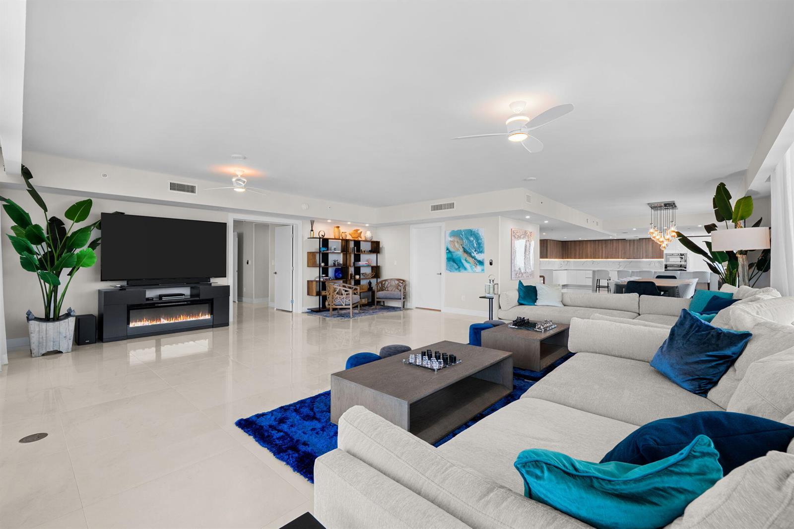 A spacious, open-concept living room features a large sectional sofa, fireplace, and tile flooring — 730 N Ocean Boulevard # 1703, Pompano Beach FL 33062, POMPANO BEACH, FL