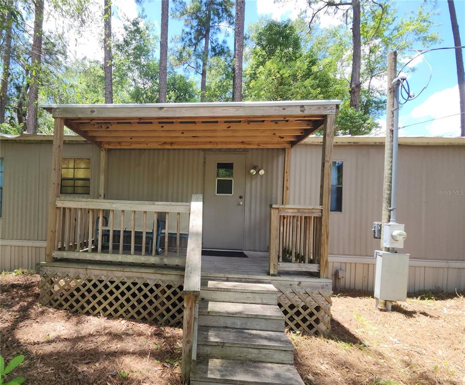 A mobile home exterior features a wooden porch with a roof and stairs — 22835 SW 117TH PLACE ROAD, DUNNELLON, FL