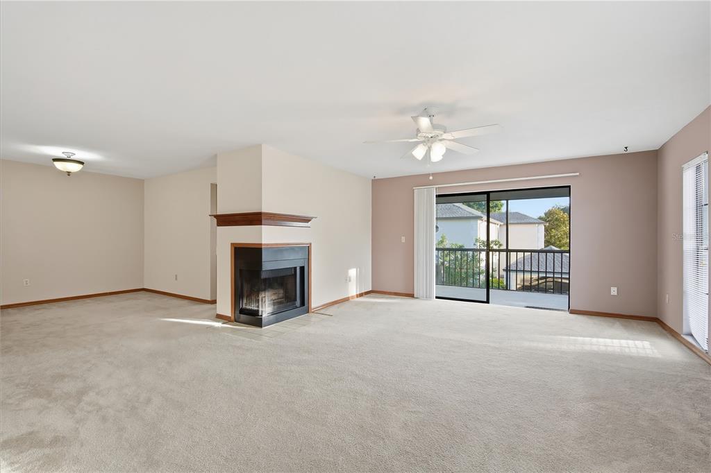 A living room features beige carpet, a corner fireplace, and a sliding glass door to a balcony — 4515 SOUTHAMPTON COURT UNIT 4515, TAMPA, FL
