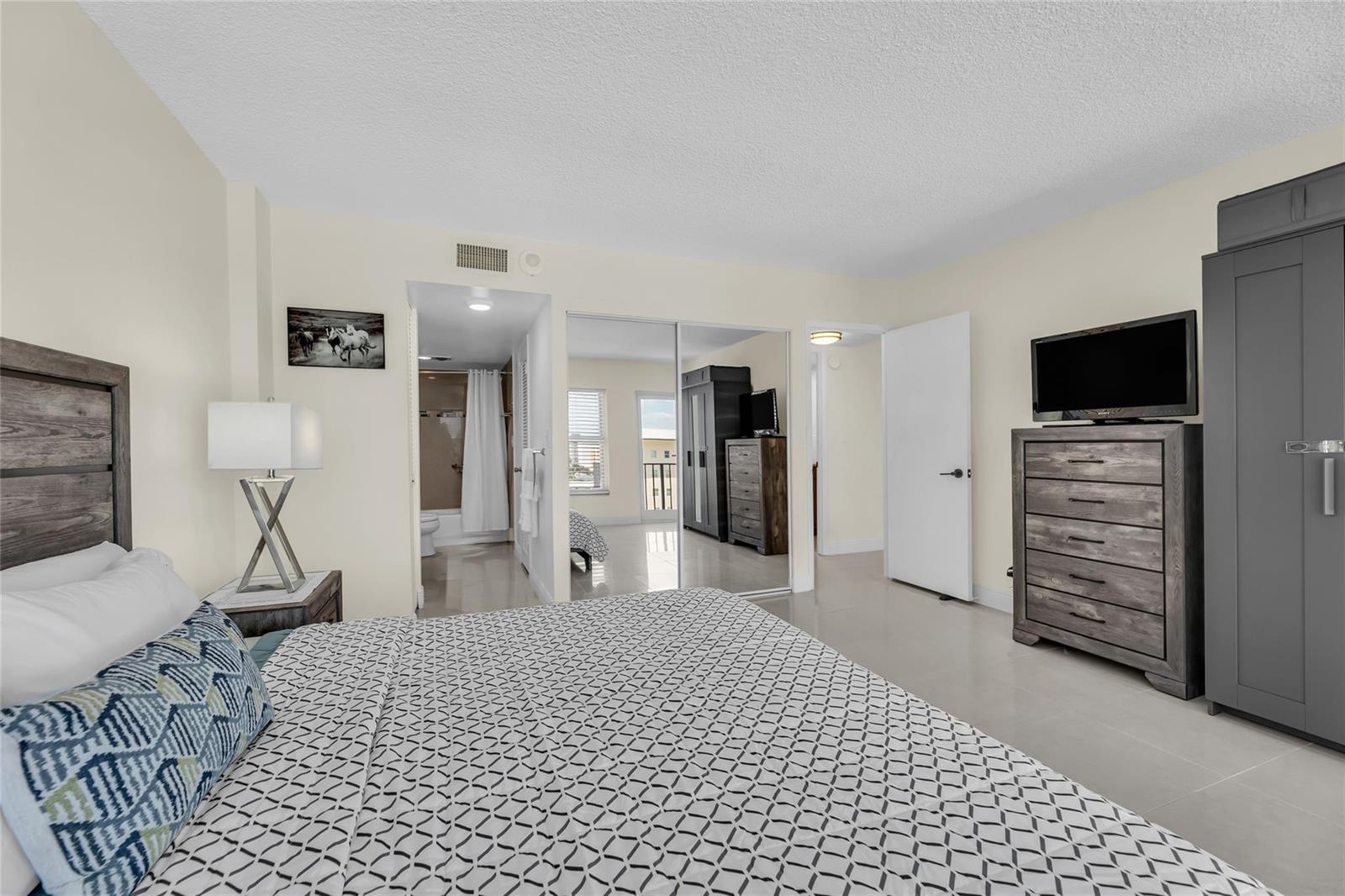 A bedroom features a bed, a dresser with a television, and an attached bathroom — 405 N Ocean Boulevard # 727, Pompano Beach FL 33062, POMPANO BEACH, FL