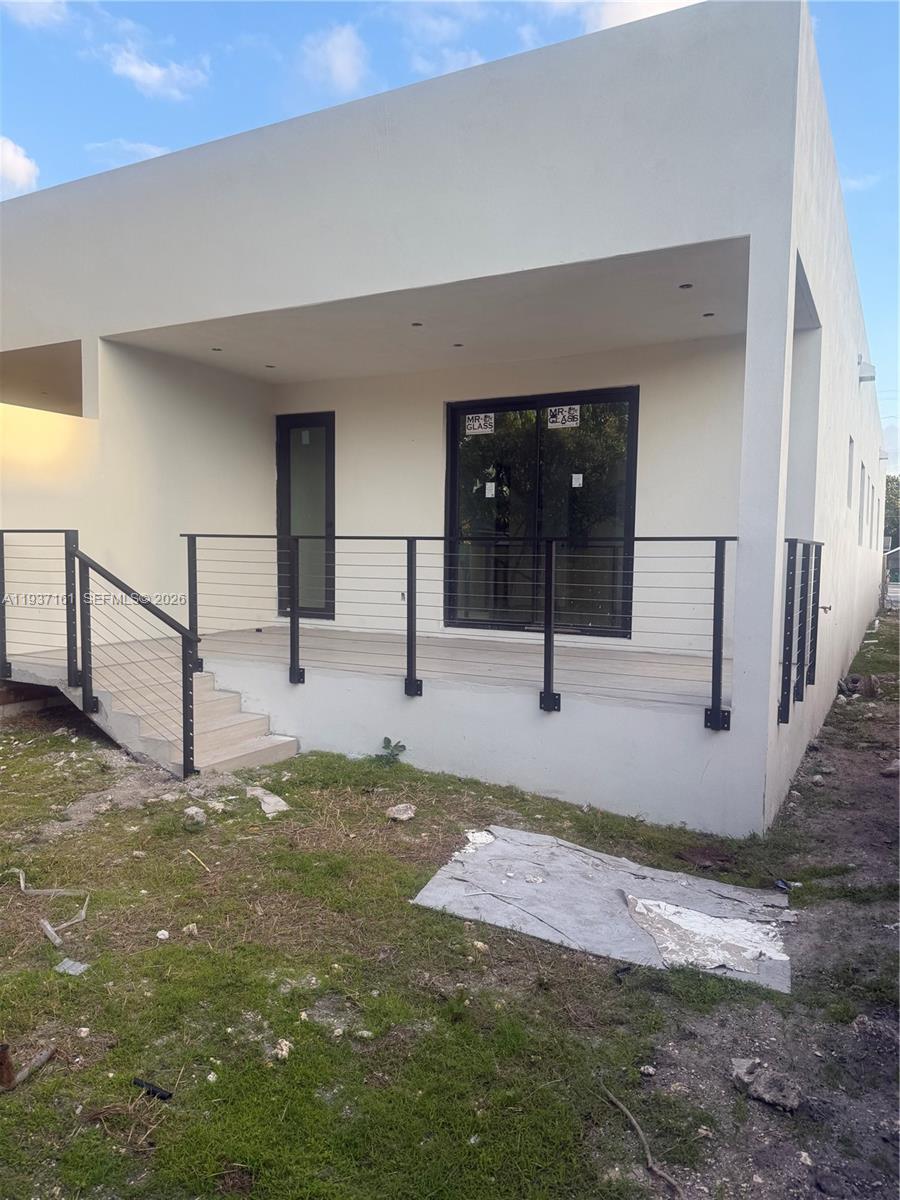A modern house exterior features a covered patio with a cable railing and stairs — 1730 NW 16th St, Miami FL 33125, MIAMI, FL