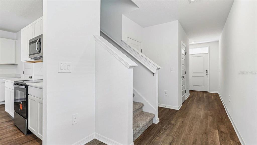 A kitchen area with white cabinets and a staircase leading to an upper level — 6064 NAVONA WAY, WINTER HAVEN, FL