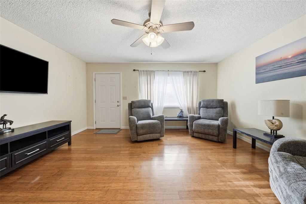 A living room features wood flooring, two gray recliners, a ceiling fan, and a television — 11224 SW 79TH TERRACE, OCALA, FL
