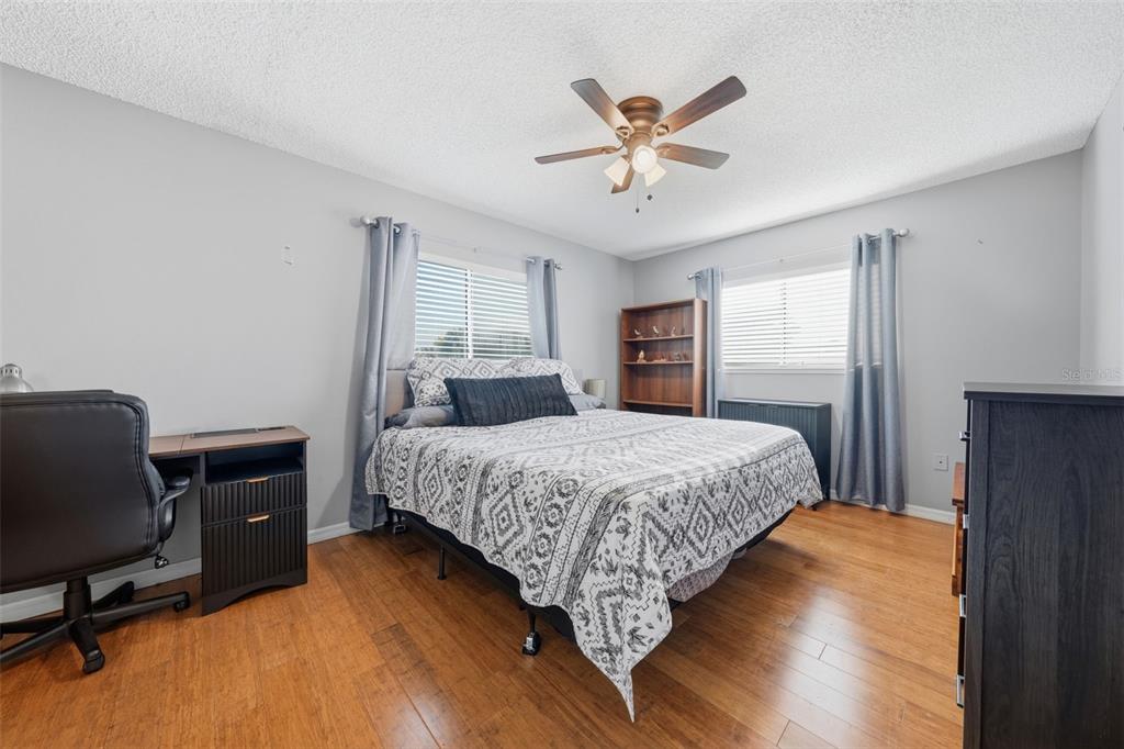 A bedroom features wood flooring, a bed with a patterned quilt, and a desk area — 11224 SW 79TH TERRACE, OCALA, FL