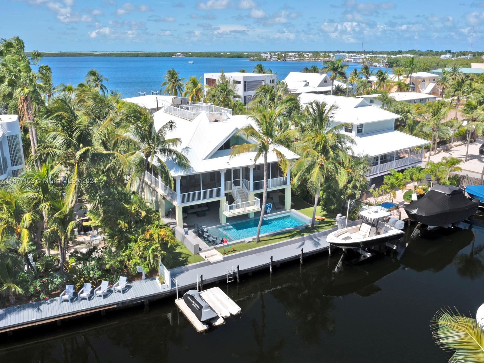 An aerial view shows a waterfront house with a pool, boat dock, and palm trees — 3 North Dr, Key Largo FL 33037, KEY LARGO, FL