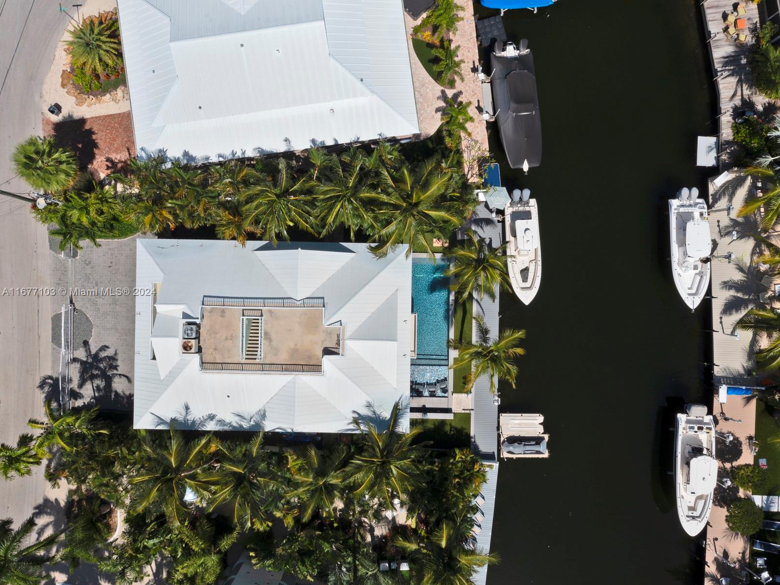 An aerial view shows a waterfront house with a pool, palm trees, and docked boats — 3 North Dr, Key Largo FL 33037, KEY LARGO, FL