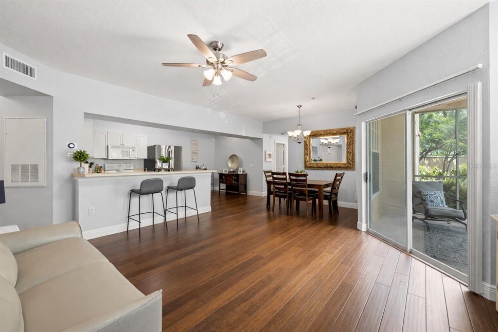 An open-concept living and dining area features wood flooring, a breakfast bar, and sliding doors — 5125 PALM SPRINGS BOULEVARD UNIT 13104, TAMPA, FL