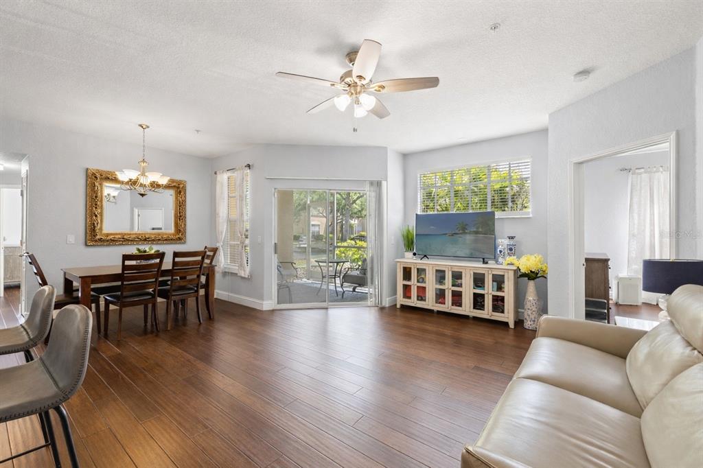 A living and dining area with wood floors, a ceiling fan, and a sliding glass door — 5125 PALM SPRINGS BOULEVARD UNIT 13104, TAMPA, FL
