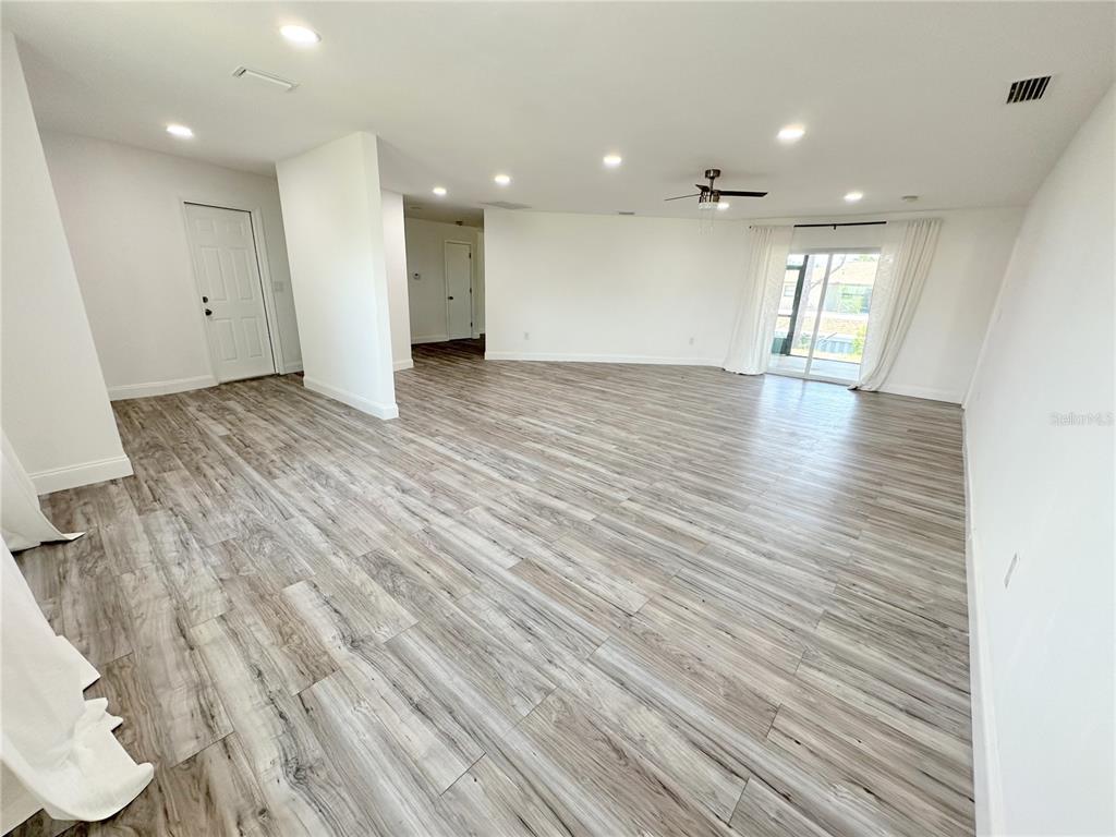 An open-concept living area features light wood-look flooring, recessed lighting, and sliding glass doors — 1081 HUMBOLDT STREET, ENGLEWOOD, FL