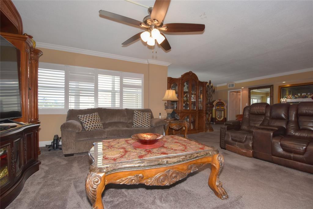 A living room features a ceiling fan, brown sofas, a coffee table, and wooden cabinetry — 111 N Pompano Beach Boulevard # 304, Pompano Beach FL 33062, POMPANO BEACH, FL