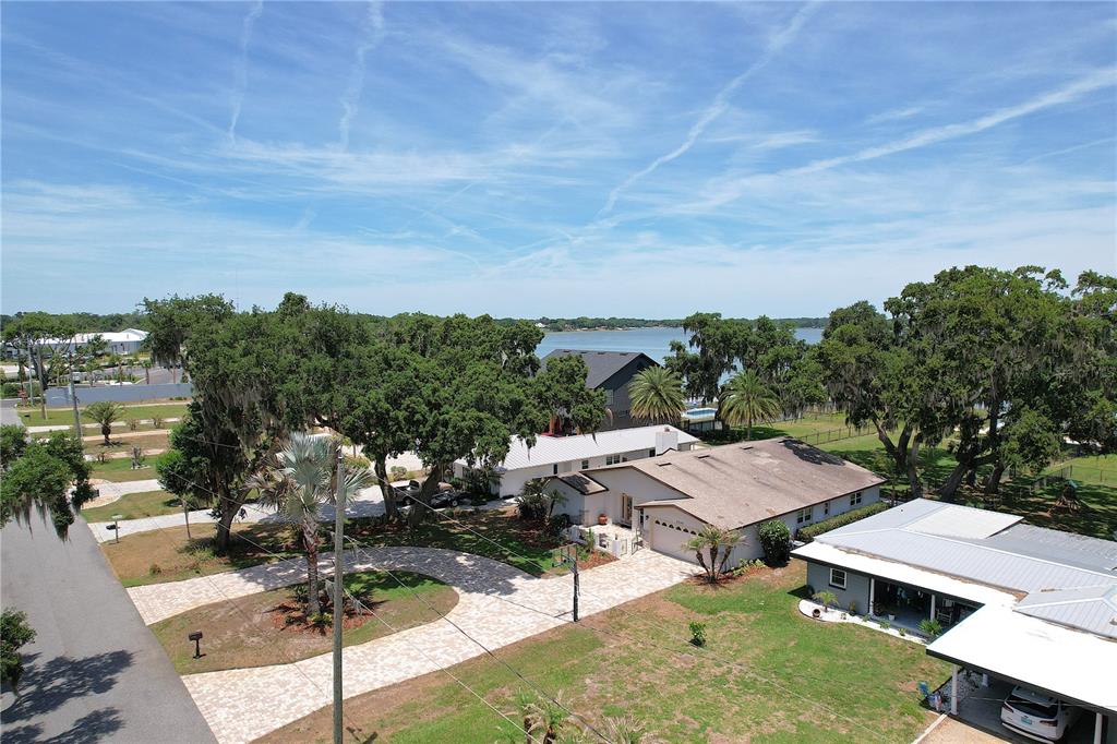 An aerial view shows a house with a paved driveway, trees, and a nearby lake — 2240 LAKE ARIANA BOULEVARD, AUBURNDALE, FL