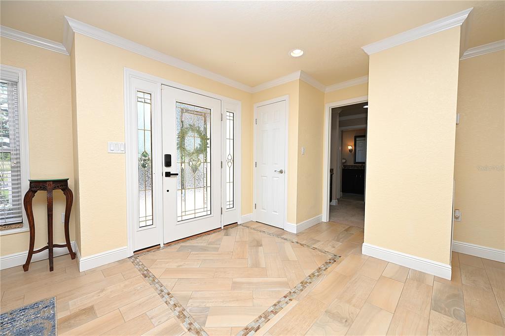 A bright foyer features a white front door, light wood flooring, and a small table — 2240 LAKE ARIANA BOULEVARD, AUBURNDALE, FL