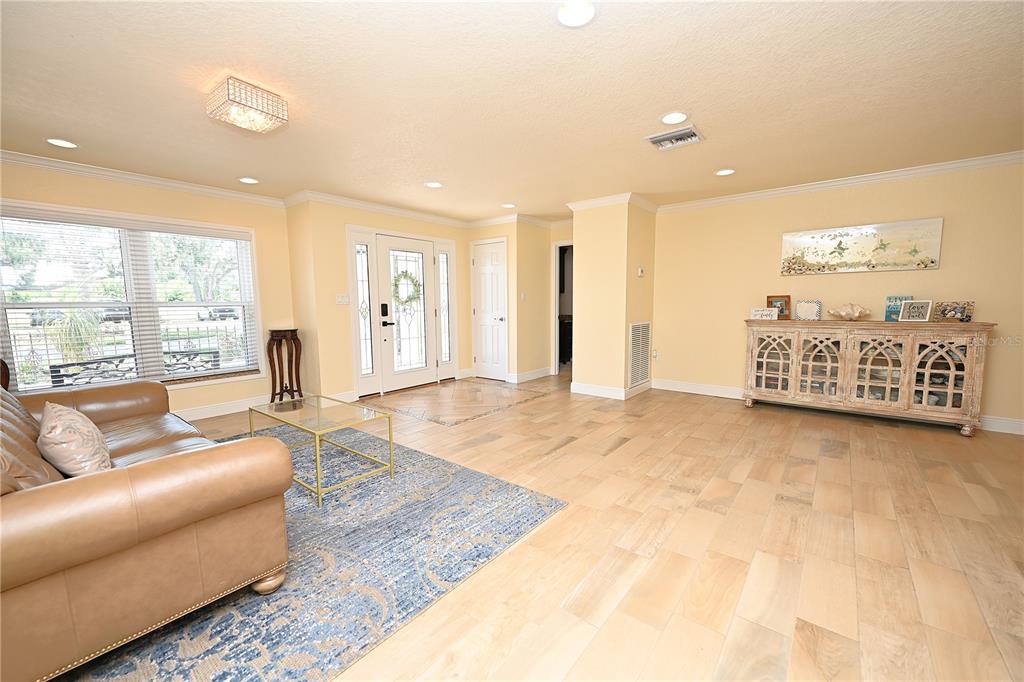 A living room with light tile floors, a tan leather sofa, and a white console table — 2240 LAKE ARIANA BOULEVARD, AUBURNDALE, FL