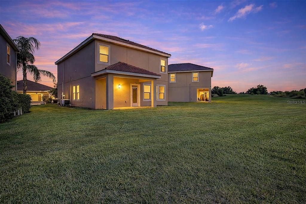 The rear exterior of a two-story house features a covered patio and a large lawn — 1059 BLACKWOLF RUN ROAD, DAVENPORT, FL