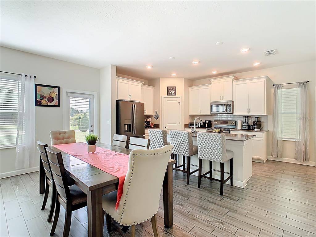 An open-concept kitchen and dining area features white cabinetry, a kitchen island, and wood-look flooring — 1059 BLACKWOLF RUN ROAD, DAVENPORT, FL