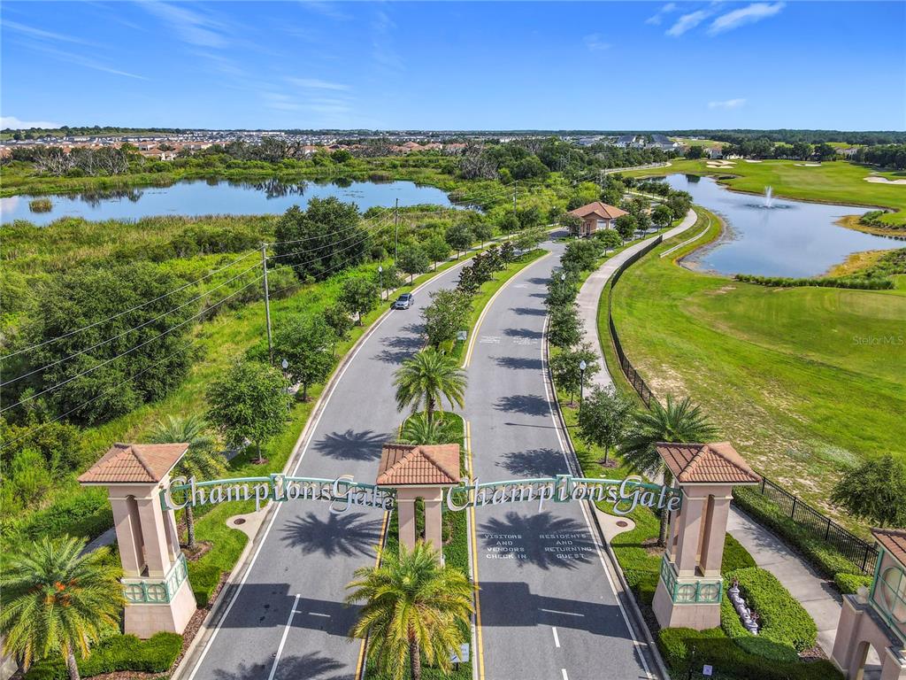 An aerial view shows the gated entrance to a community with palm trees and ponds — 1059 BLACKWOLF RUN ROAD, DAVENPORT, FL