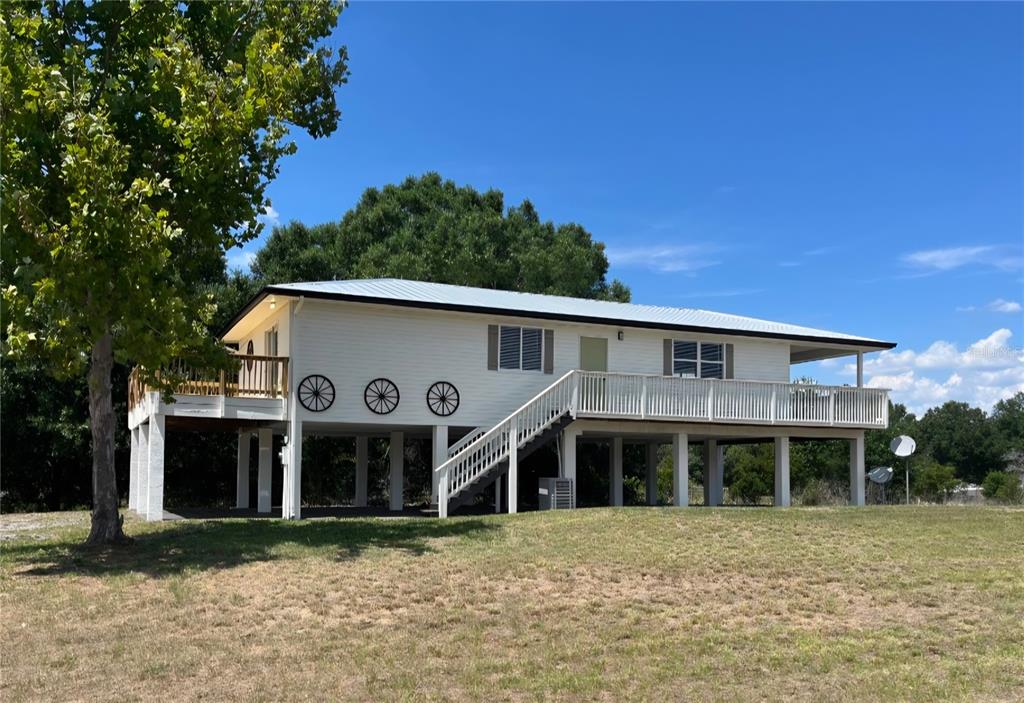 An elevated white house with a metal roof, wraparound deck, and stairs leading to the entrance — 464 LOGUE ROAD, MYAKKA CITY, FL