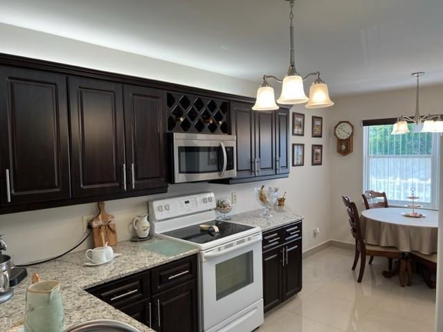 A kitchen features dark wood cabinets, granite countertops, a white stove, and a dining area — 2603 NW 103rd Avenue, Sunrise FL 33322, SUNRISE, FL