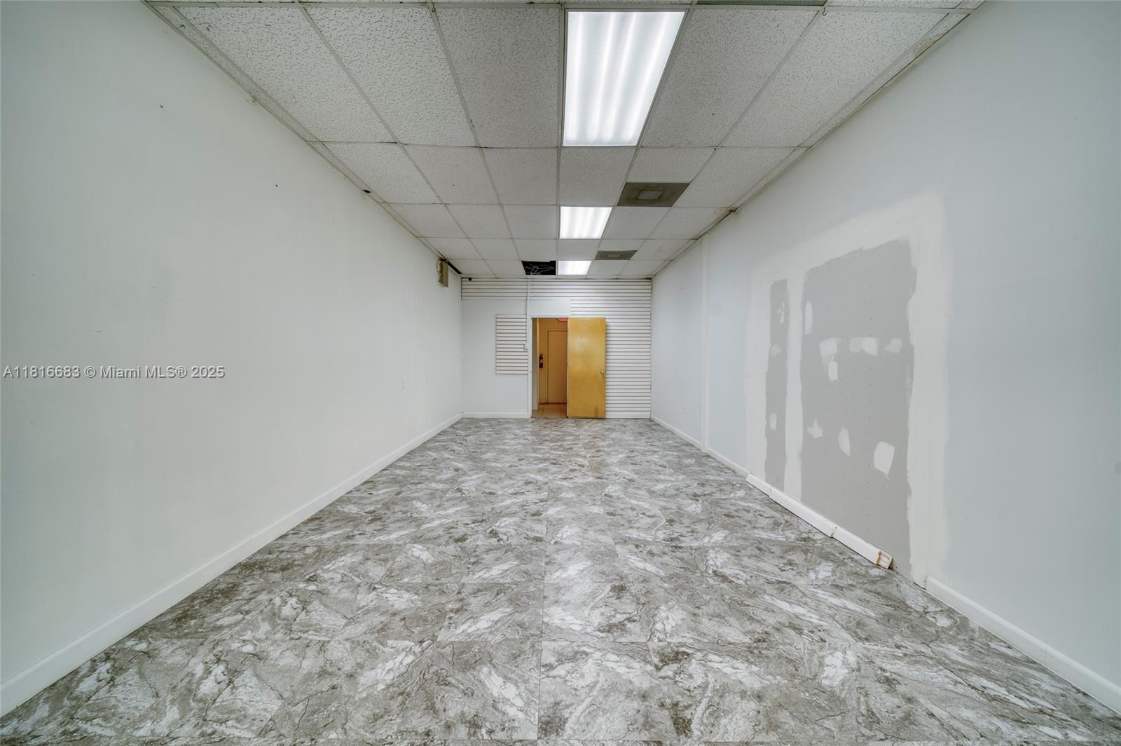 An empty rectangular commercial room features white walls, a drop ceiling, and gray tiled flooring — 363 E 1st Ave, Miami FL 33010, MIAMI, FL