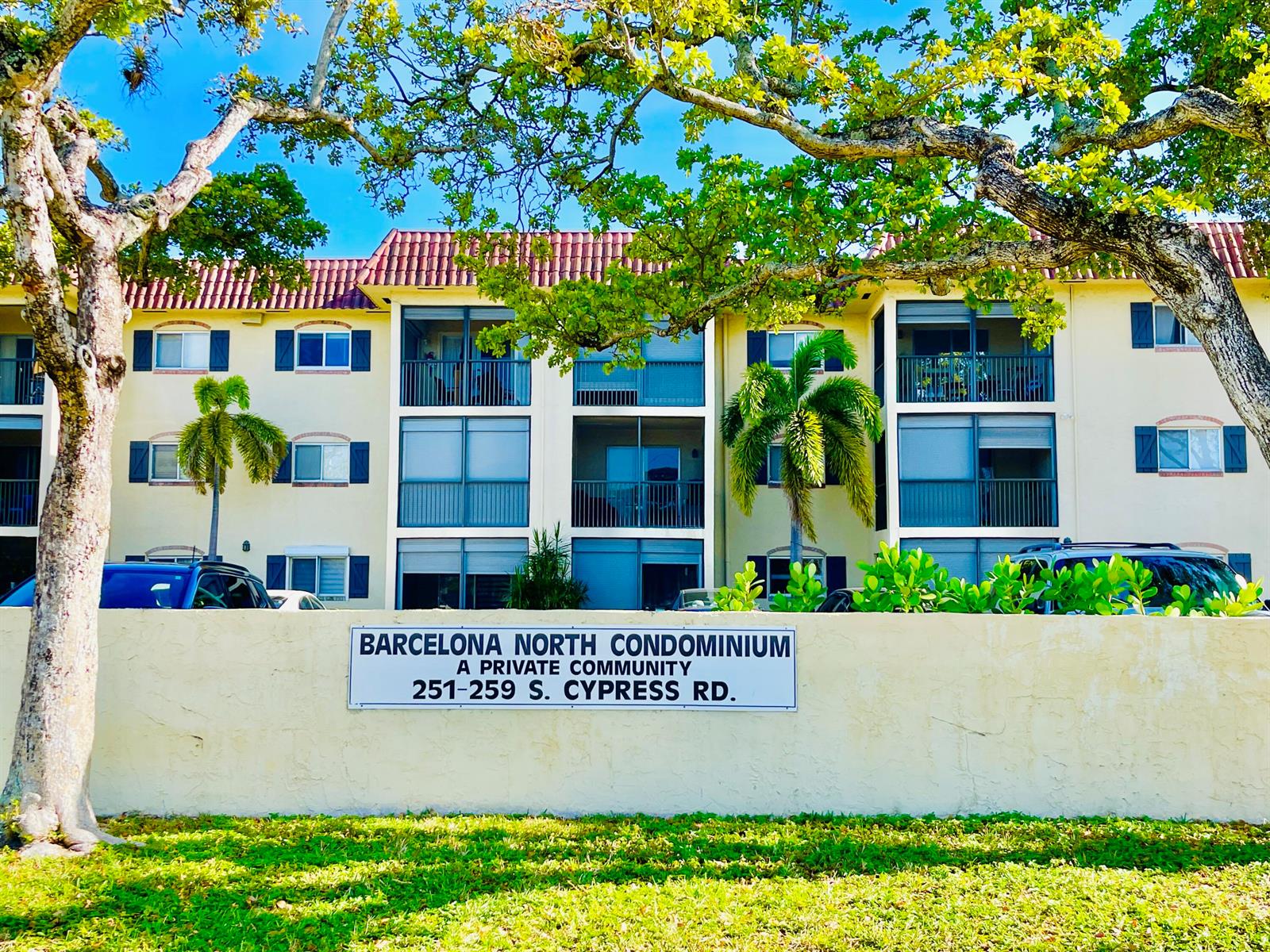 A three-story apartment building with a beige exterior, red tile roof, and a front wall — 257 S Cypress Road # 442, Pompano Beach FL 33060, POMPANO BEACH, FL