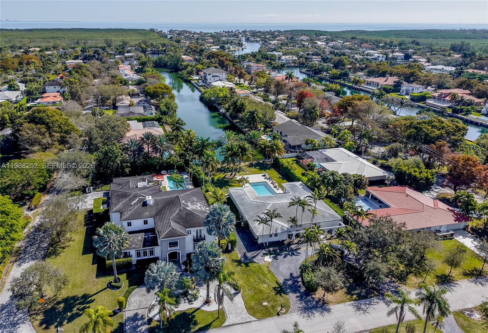 An aerial view shows several waterfront houses with swimming pools and palm trees along a canal — 12755 SW 57th Ave, Coral Gables FL 33156, CORAL GABLES, FL