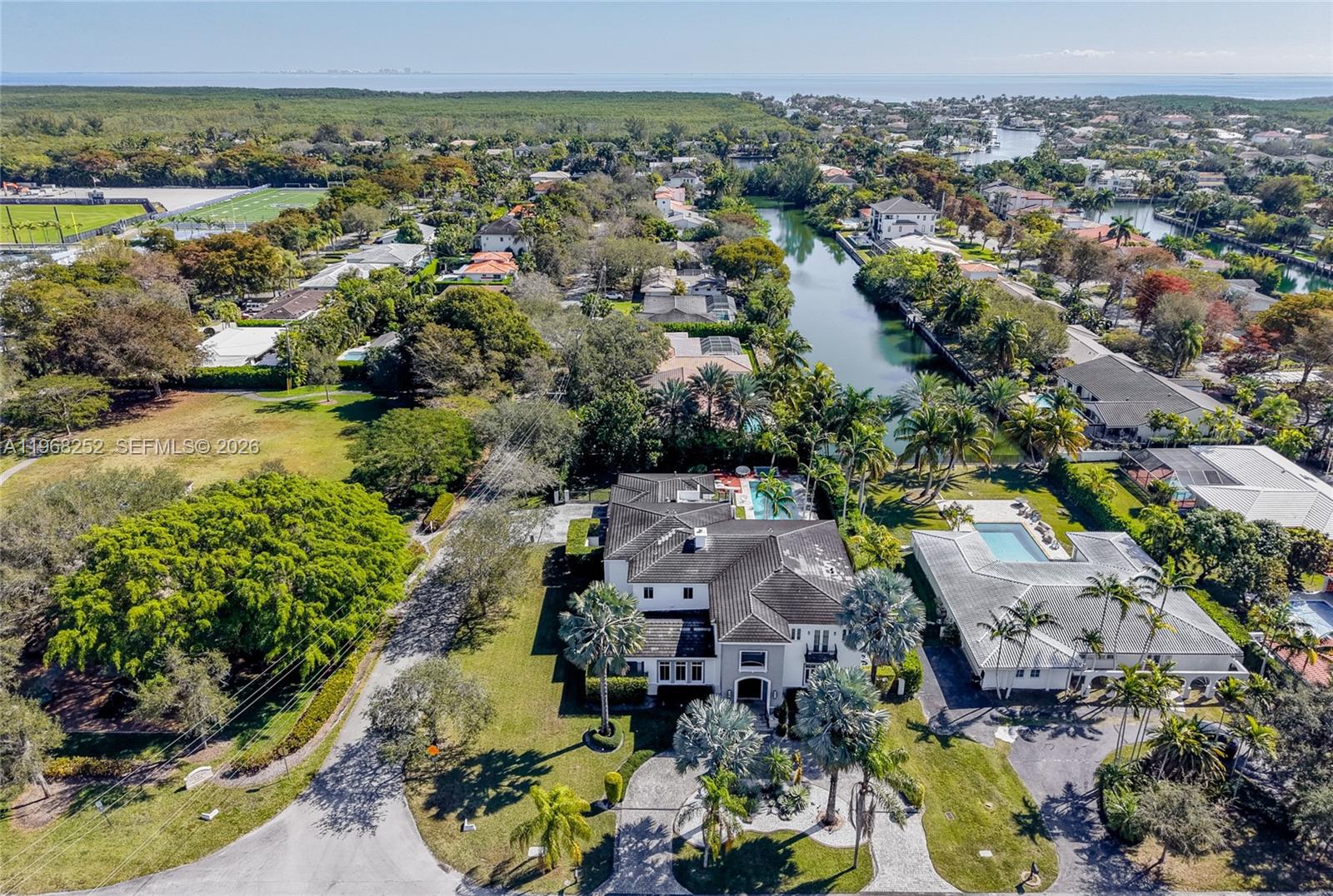 An aerial view shows a large house with a pool, surrounded by trees and canals — 12755 SW 57th Ave, Coral Gables FL 33156, CORAL GABLES, FL