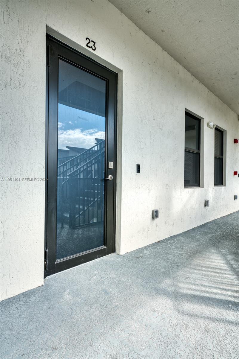 A black-framed glass door labeled 23 sits on a concrete walkway beside two windows — 7831 NW 104th Ave # 23, Doral FL 33178, DORAL, FL