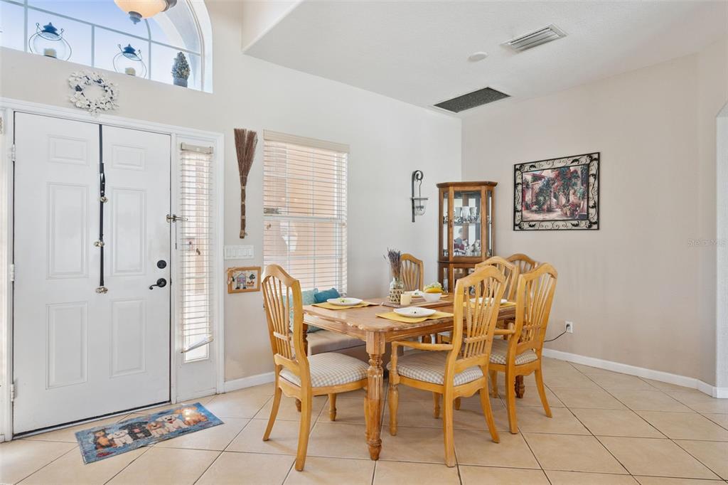 A dining area with a wooden table, chairs, and a corner bench near the entryway — 2930 WHITE CEDAR CIRCLE, KISSIMMEE, FL