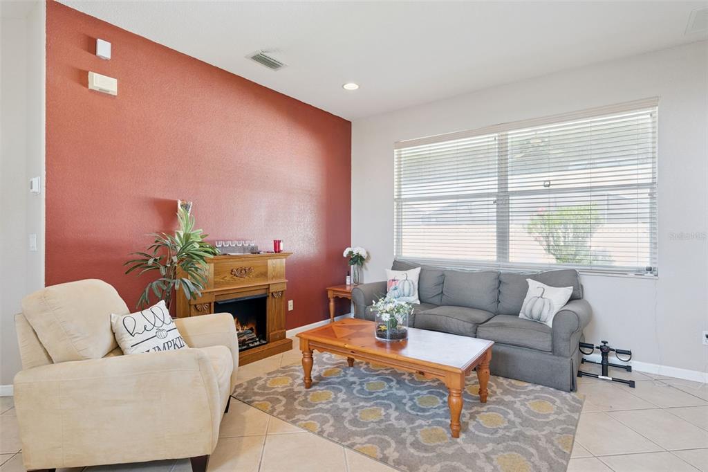A living room features a red accent wall, a fireplace, a sofa, and an armchair — 2930 WHITE CEDAR CIRCLE, KISSIMMEE, FL
