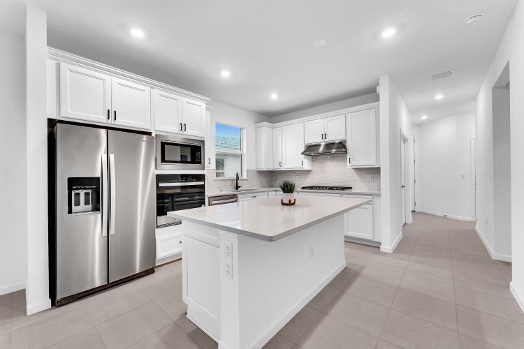 A modern kitchen features white cabinets, stainless steel appliances, and a central island — 1133 Haven Circle, Vero Beach FL 32960, VERO BEACH, FL