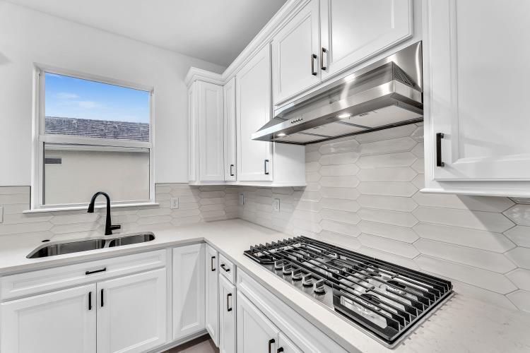 A modern kitchen features white cabinets, a stainless steel range hood, and a tiled backsplash — 1133 Haven Circle, Vero Beach FL 32960, VERO BEACH, FL