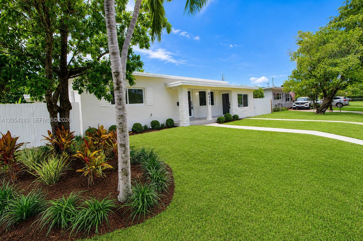 A white single-story house features a front lawn, a paved walkway, and tropical landscaping — 6410 SW 17th St, West Miami FL 33155, WEST MIAMI, FL