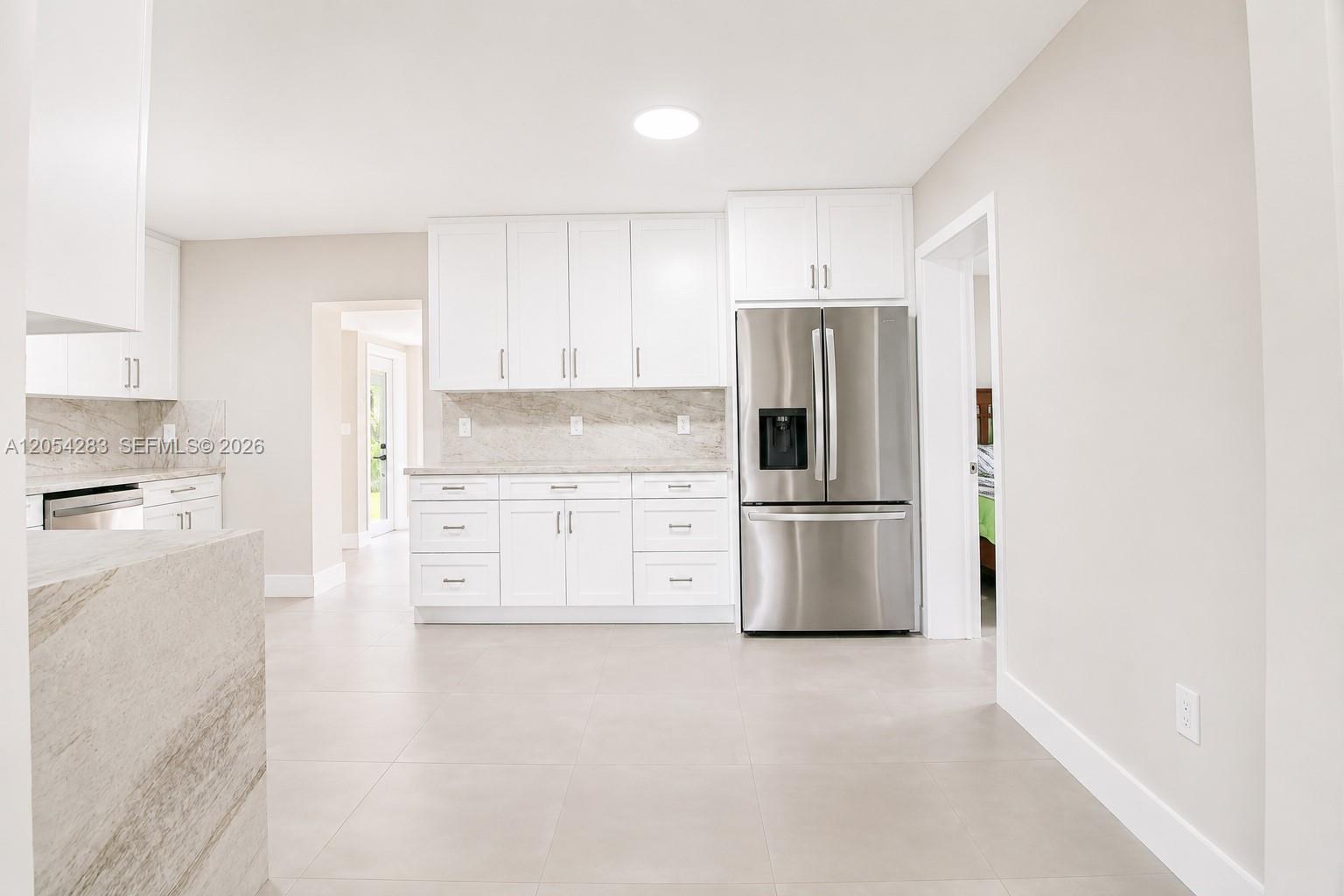 A modern kitchen features white cabinetry, stainless steel appliances, and light-colored stone countertops — 6410 SW 17th St, West Miami FL 33155, WEST MIAMI, FL